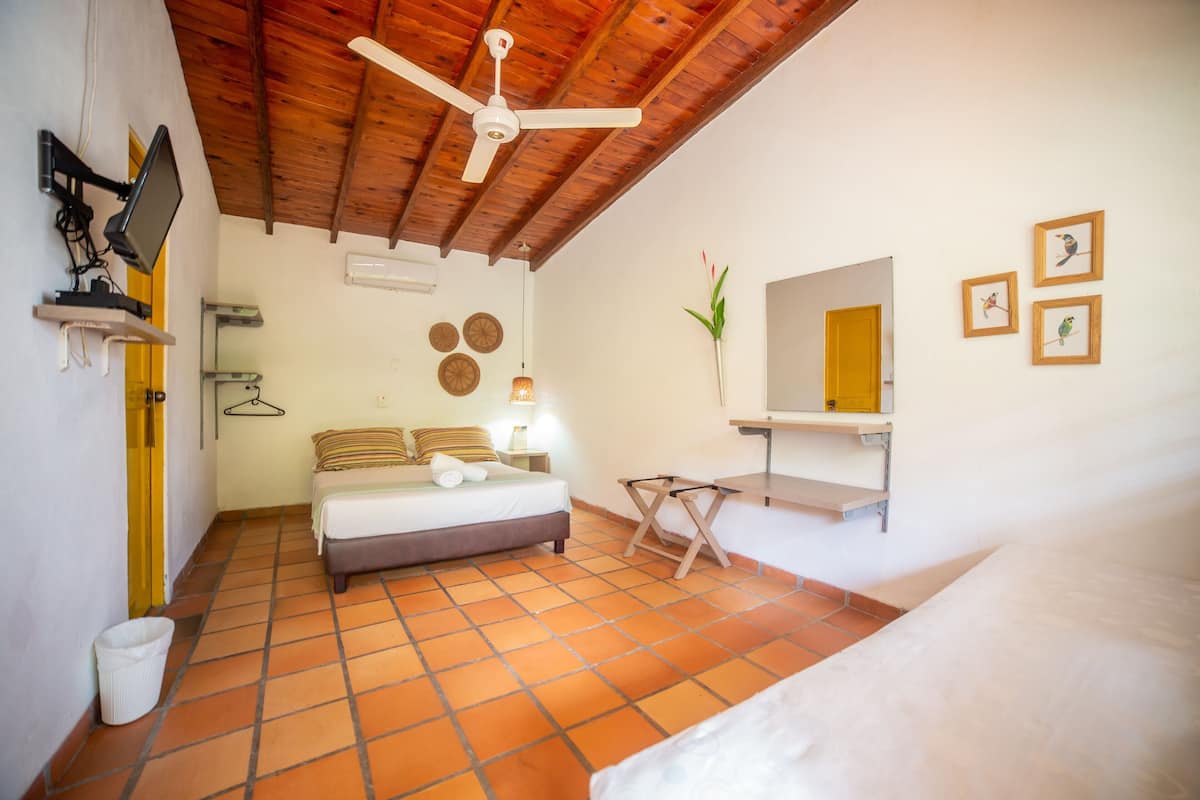 A bedroom with a bed, a desk, a chair, a ceiling fan, a mirror, and wall decorations.