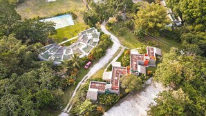 An aerial view of a resort with multiple buildings, a swimming pool, and lush greenery. - Los Colores Ecoparque (Puerto Triunfo)