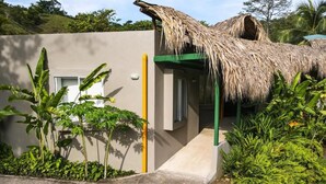 A building with a thatched roof, a concrete pathway, and lush greenery. - Los Colores Ecoparque (Puerto Triunfo)