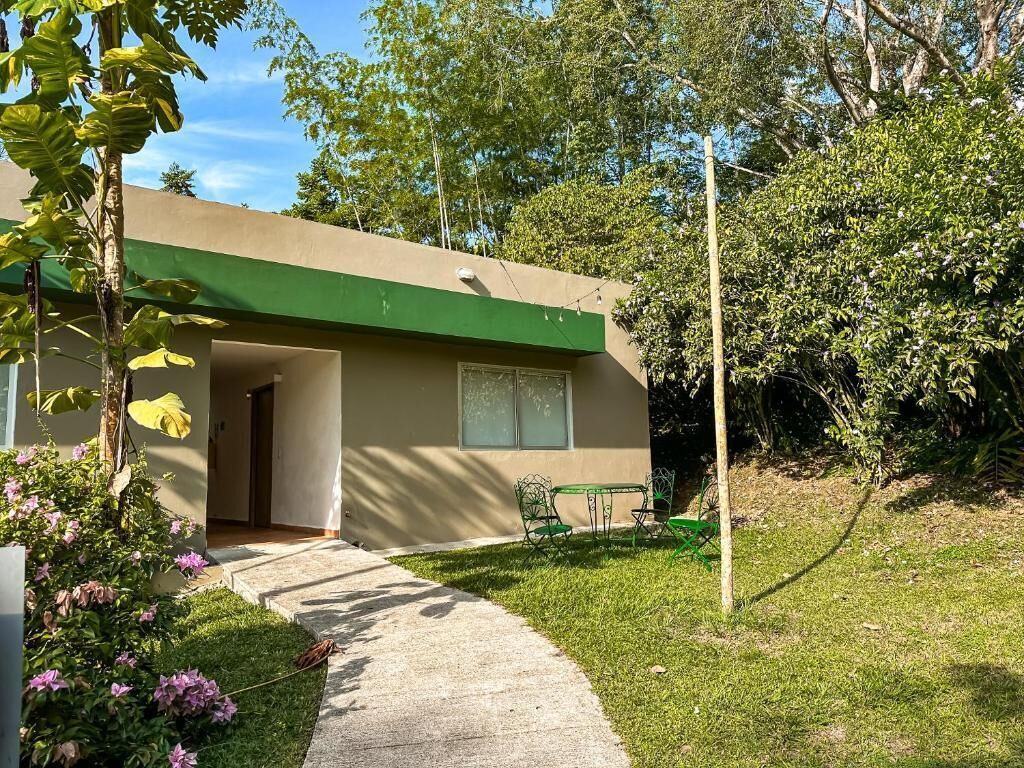 A single-story building with a green roof and a small patio area with a table and chairs.