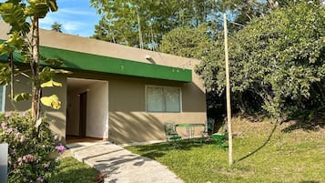 A single-story building with a green roof and a small patio area with a table and chairs.