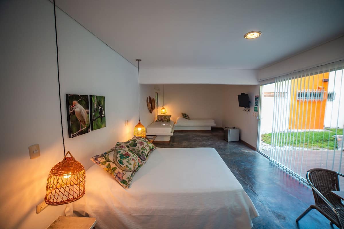 A modern bedroom with a bed, bedside lamps, a small table, and a chair.