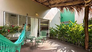 A patio with a hammock, two chairs, and a green wall with plants. - Los Colores Ecoparque (Puerto Triunfo)