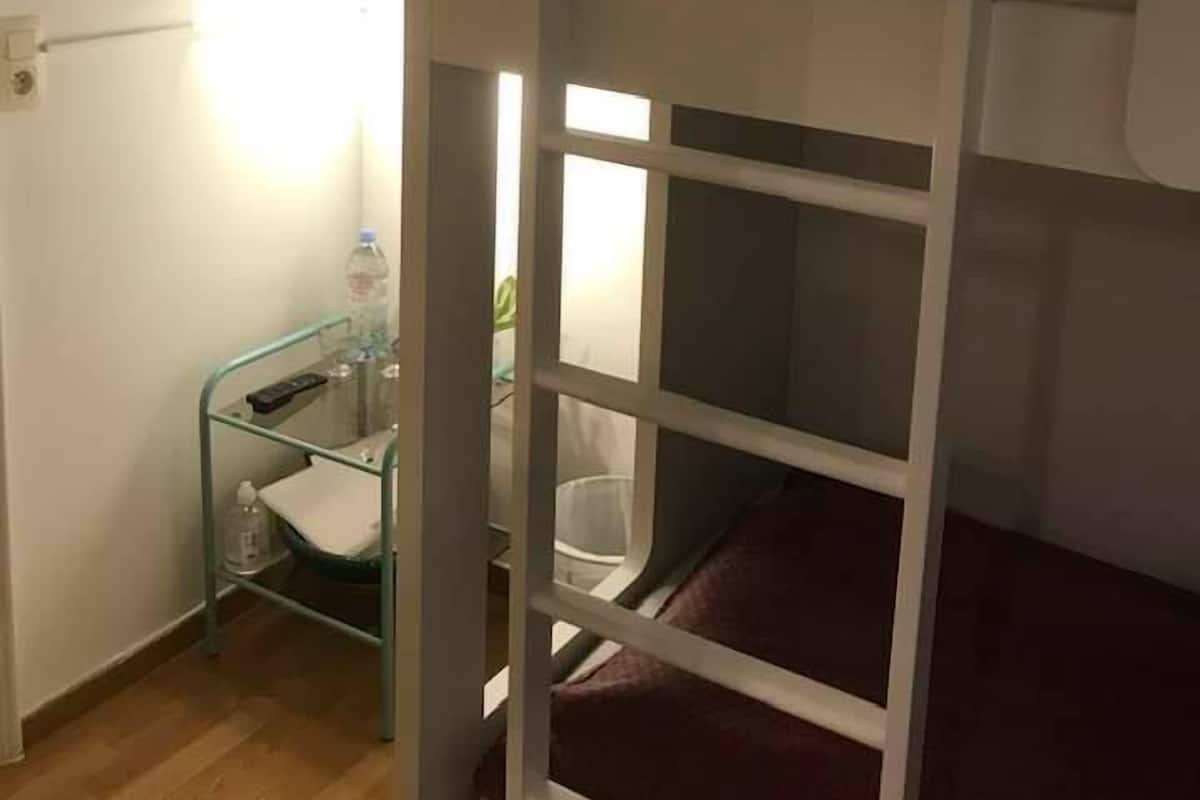 A bunk bed room with a small table and a framed picture on the wall.