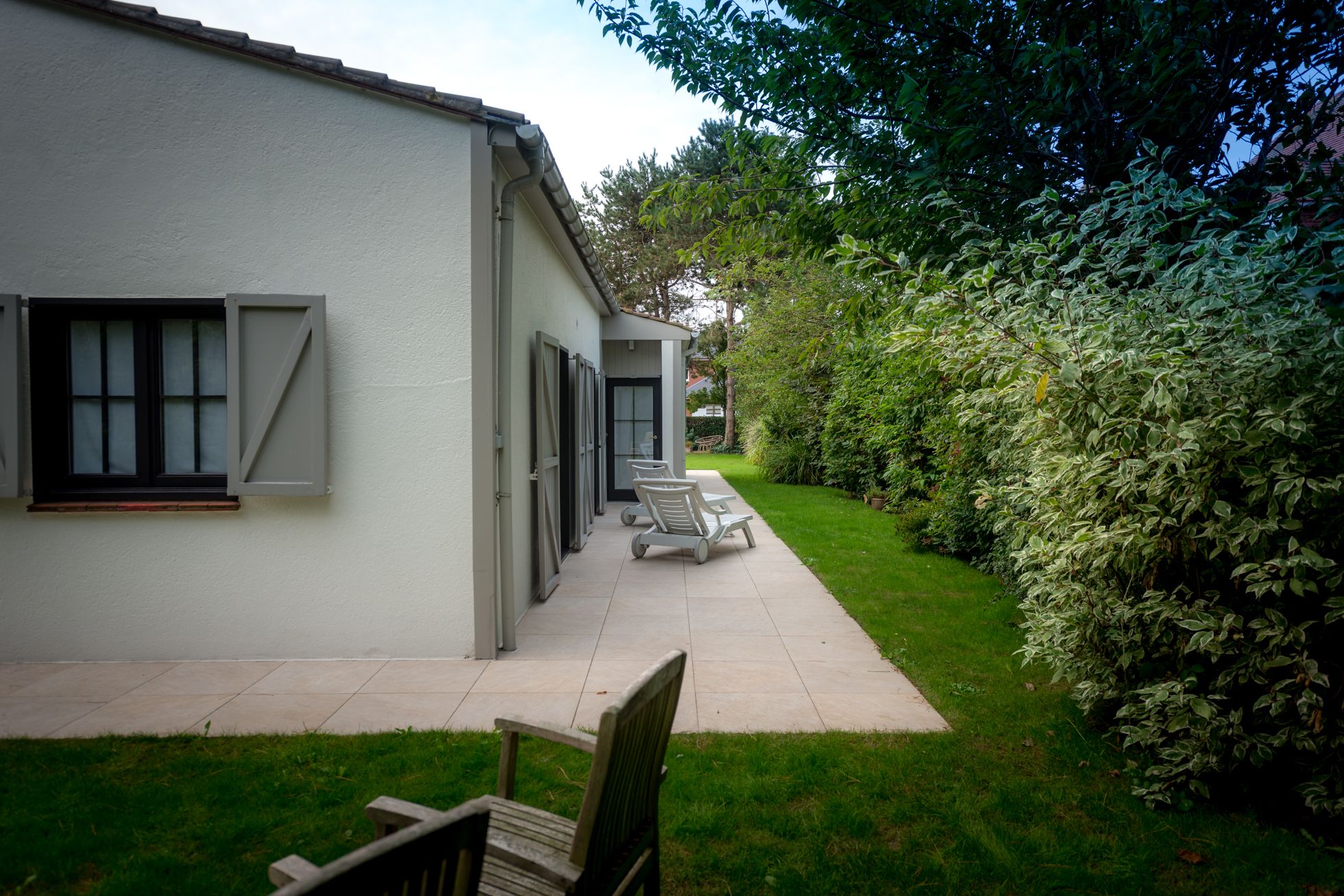 Una casa moderna con un patio, césped y seto.