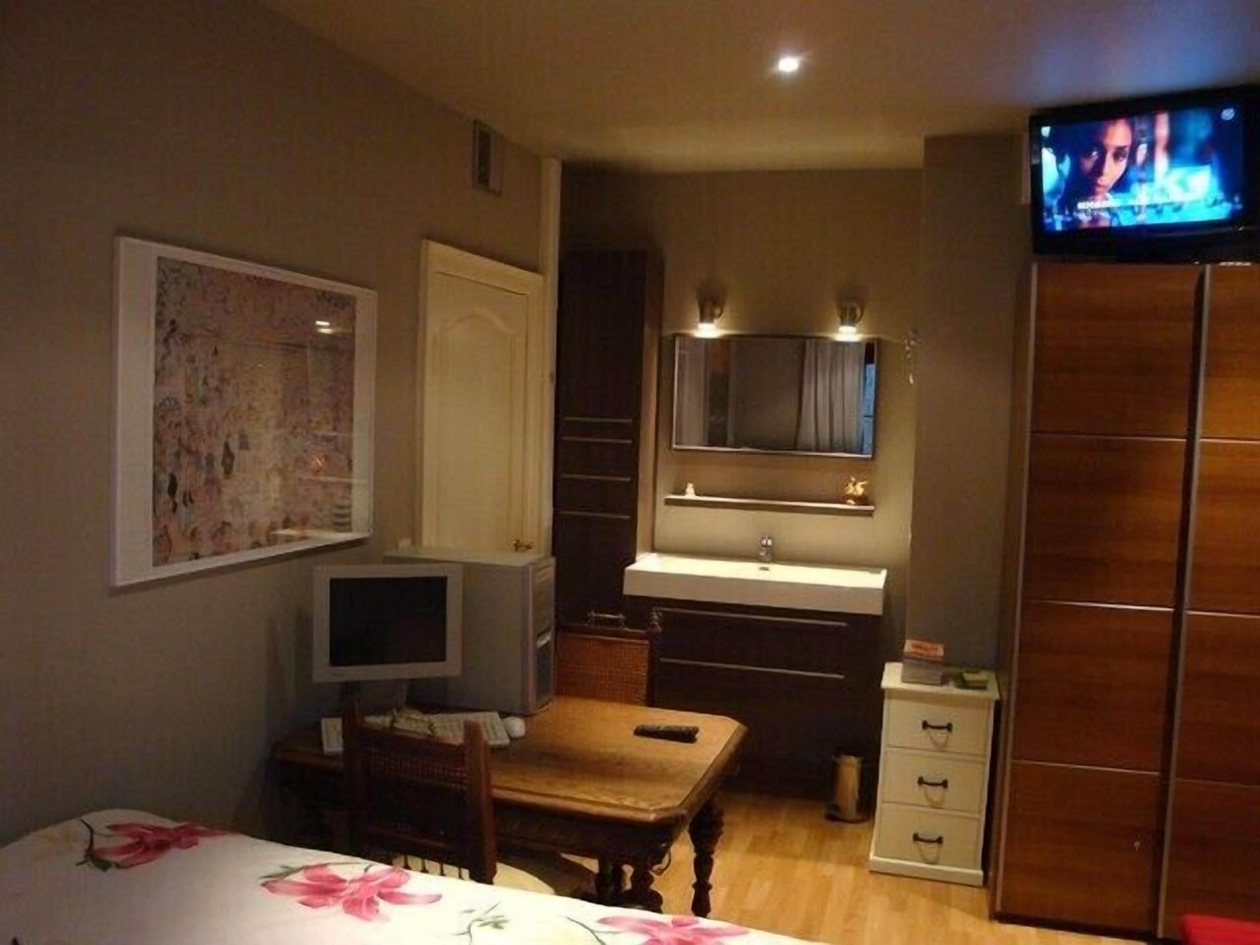 A hotel room with a bed, a desk, a television, a mirror, and a wardrobe.
