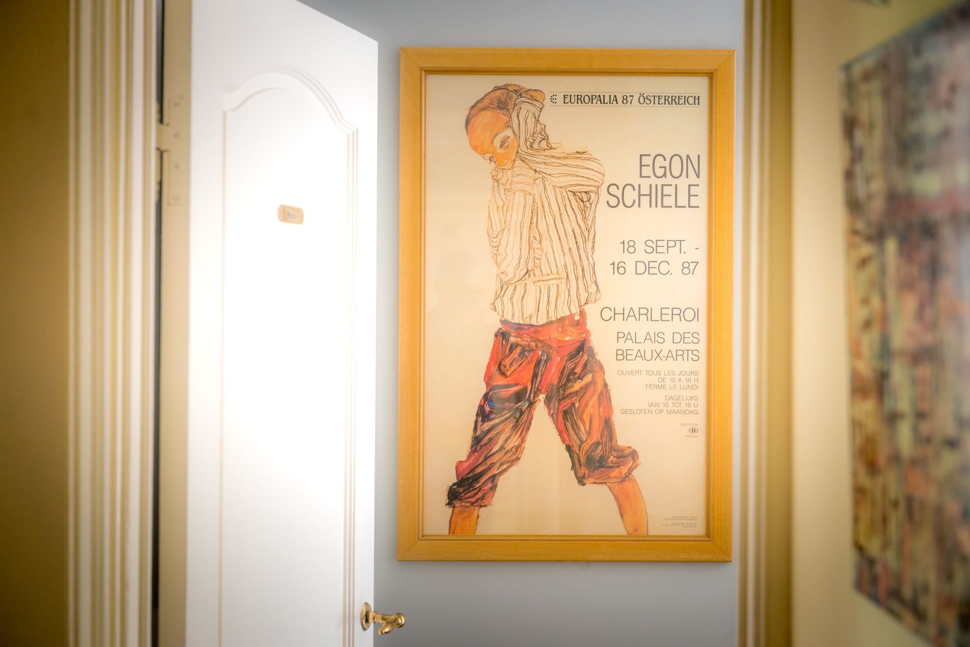 A framed artwork on a wall in a hallway.
