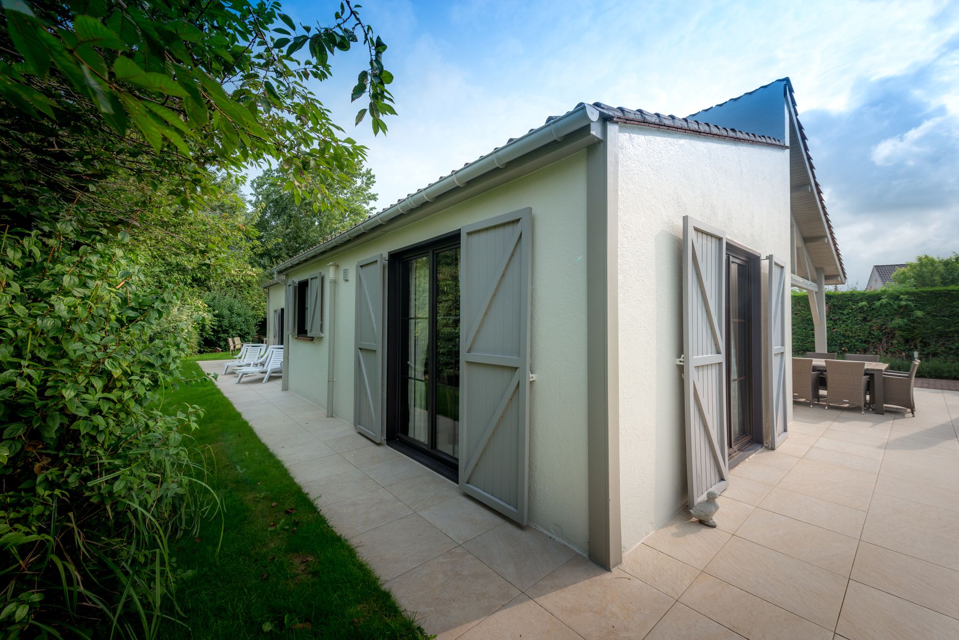 A small, single-story building with a patio area, a sliding glass door, and a covered outdoor seating area.