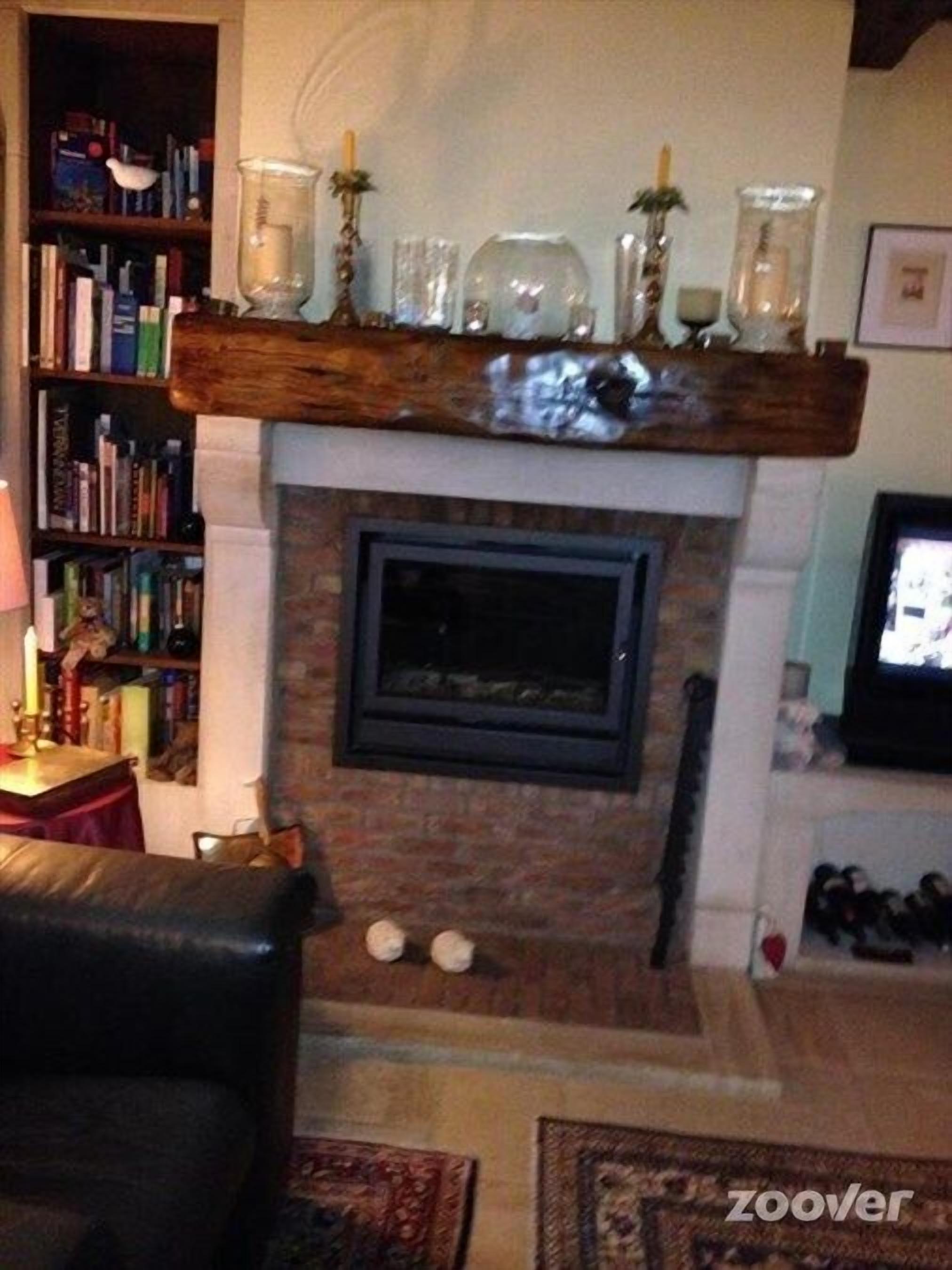 A cozy living room with a fireplace, bookshelves, a leather sofa, and a coffee table.