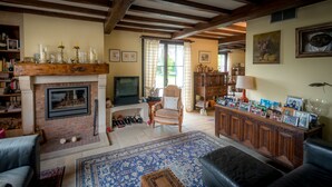 A cozy living room with a fireplace, a television, a comfortable chair, and a bookshelf. - B&B Yaca (De Haan)