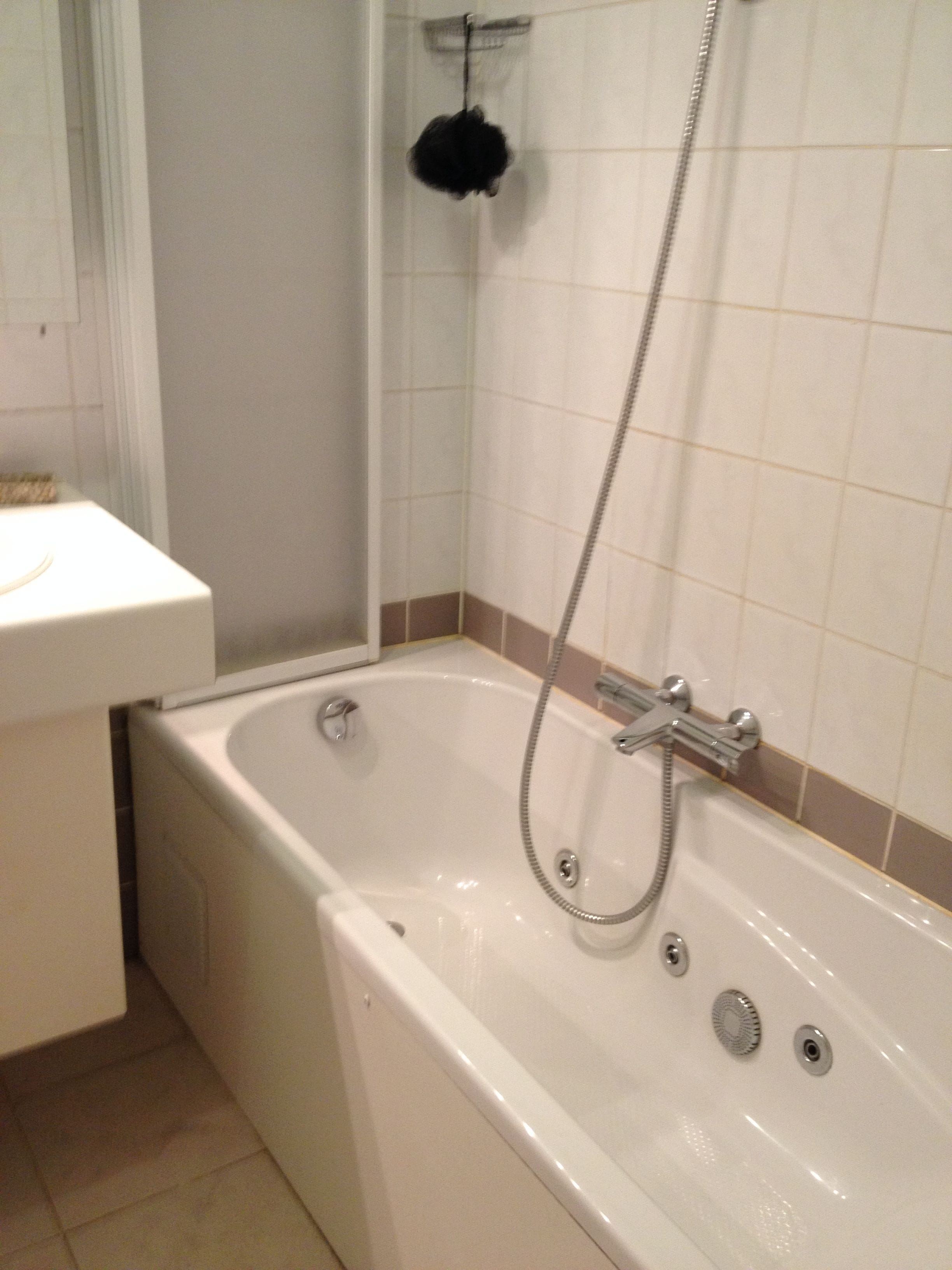 A bathroom with a white bathtub, a shower, and a sink.