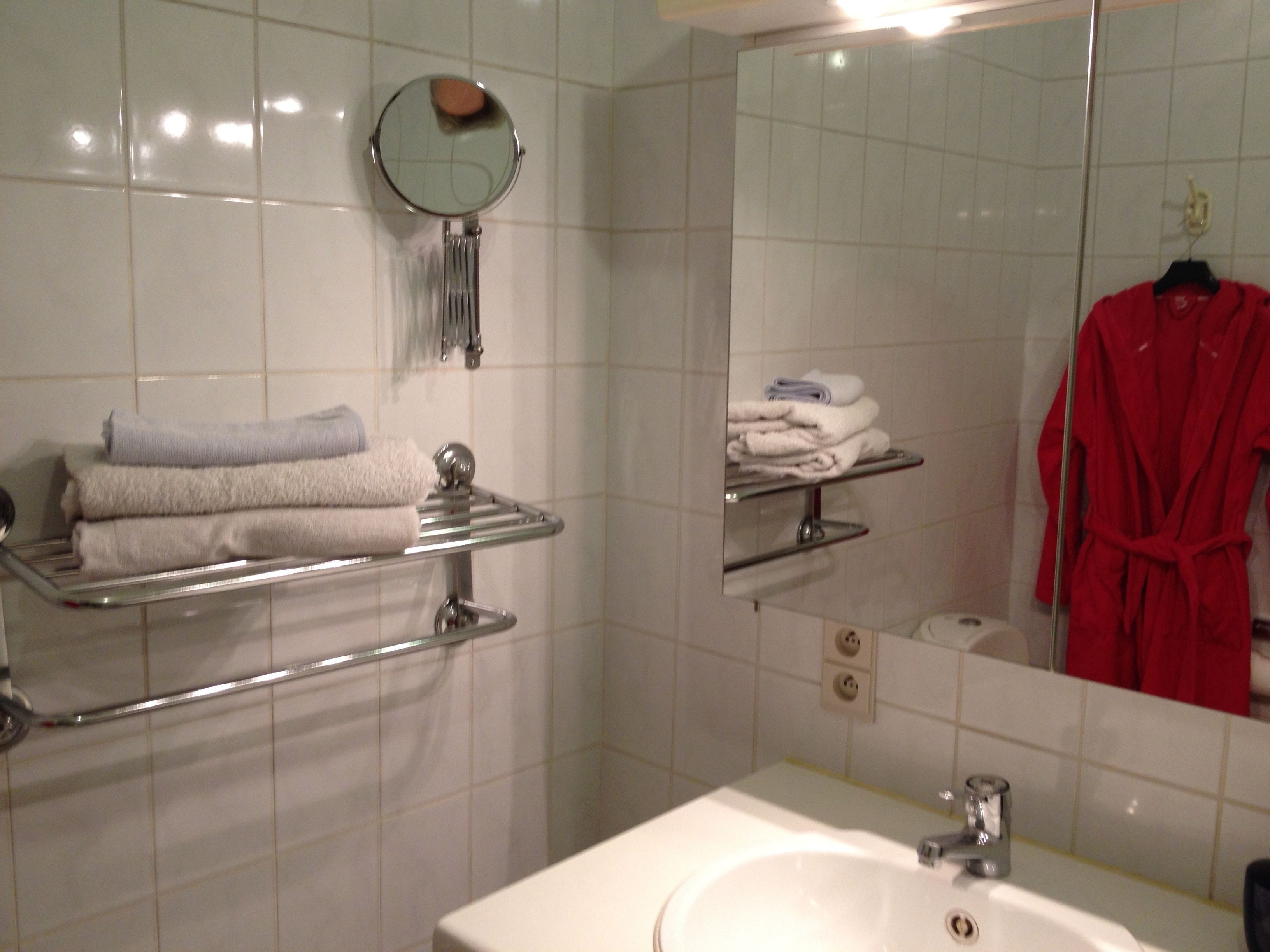 A bathroom with a sink, mirror, towel rack, and shelves for toiletries.