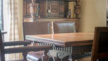 Uma sala de jantar com mesa e cadeiras de madeira, um armário decorativo com pratos e um painel de parede texturizado.