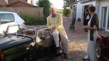 Une voiture ancienne est garée dans une allée, avec une maison en arrière-plan.