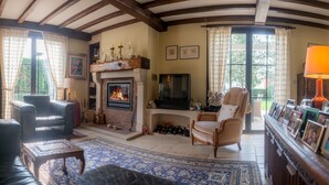 A cozy living room with a fireplace, leather sofas, and a large rug. - B&B Yaca (De Haan)