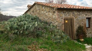 Een gebouw van steen met een pannendak, omgeven door een grote cactusgaard.