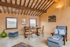 Un comedor con mesa y sillas de madera, un sofá y un jarrón verde.