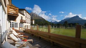 Une terrasse en bois avec des chaises longues et une vue sur un paysage montagneux.