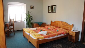Un dormitorio con cama de madera, una mesita de noche, una silla, una ventana con cortinas y un reloj de pared.