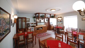Amplia sala de estar con mesa de comedor, sillas, zona de cocina con armarios y un ventanal que proporciona luz natural.