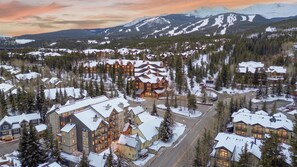 A large lodge with multiple buildings, surrounded by snow-covered trees and mountains in the background. - Wedgewood Lodge (Breckenridge)
