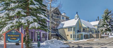 A lodge with a snow-covered sign, a staircase, and a mix of colorful buildings.