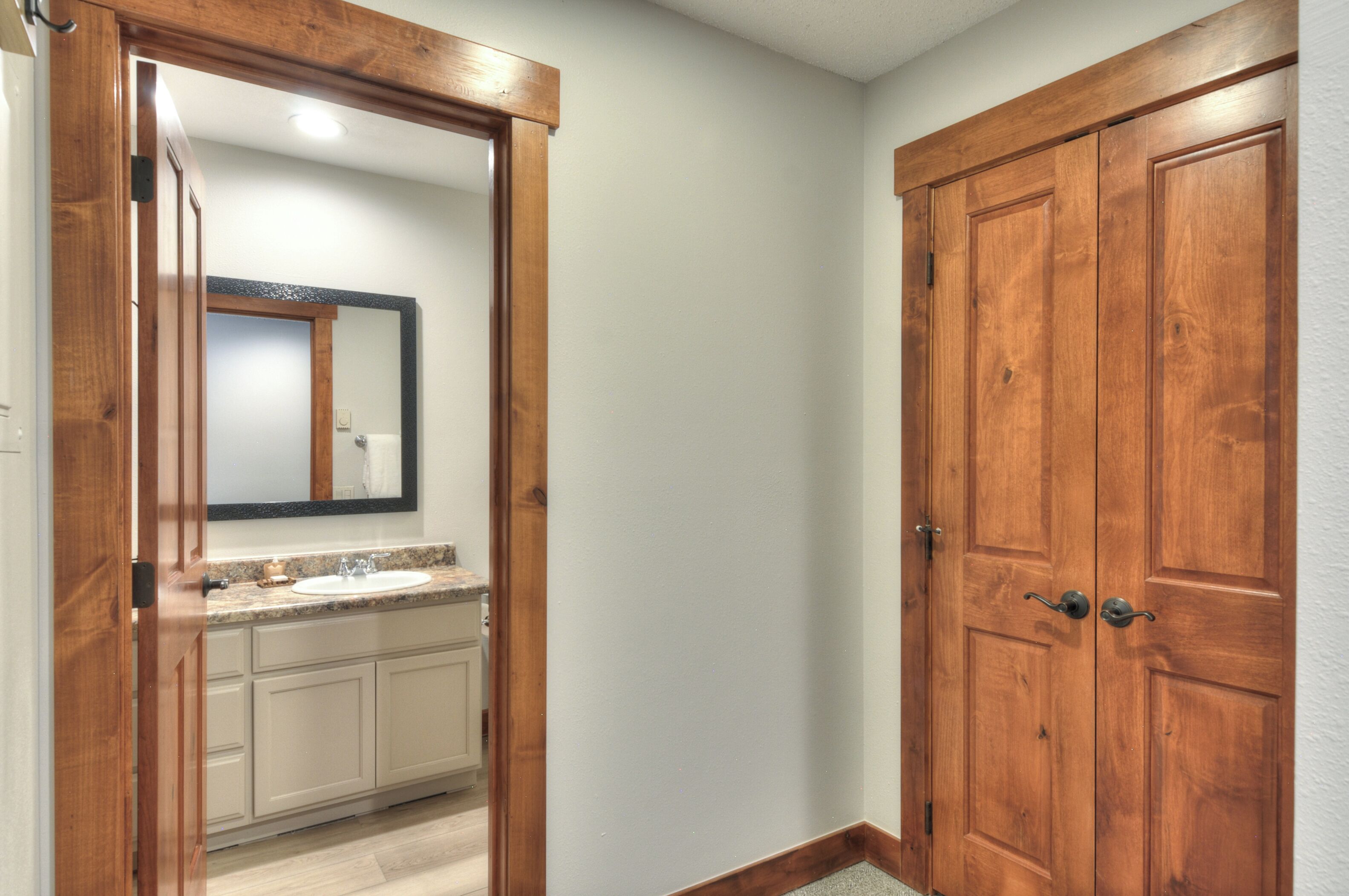 Une salle de bain avec une porte en bois, un miroir et un lavabo.