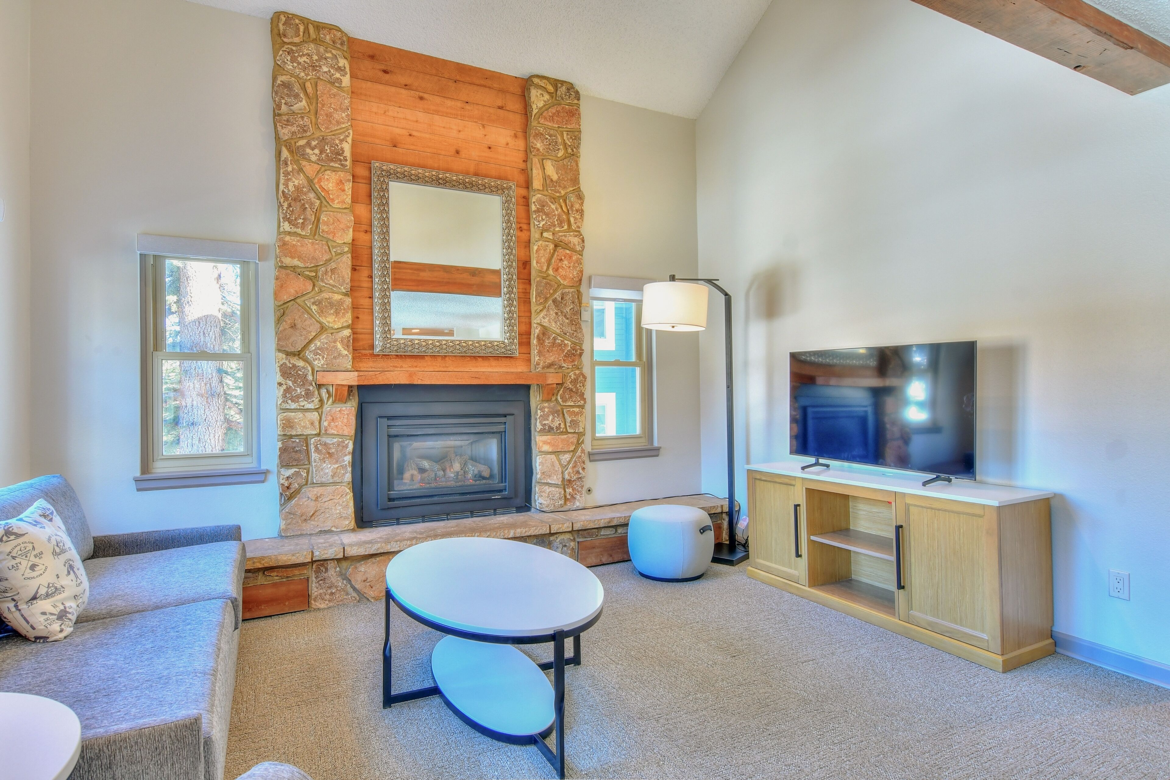 A living room with a stone fireplace, a television, and a light-colored sofa.