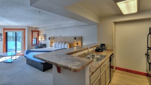 A modern hotel room with a large bed, a kitchenette, a dining area, and a bathroom. - Wedgewood Lodge (Breckenridge)
