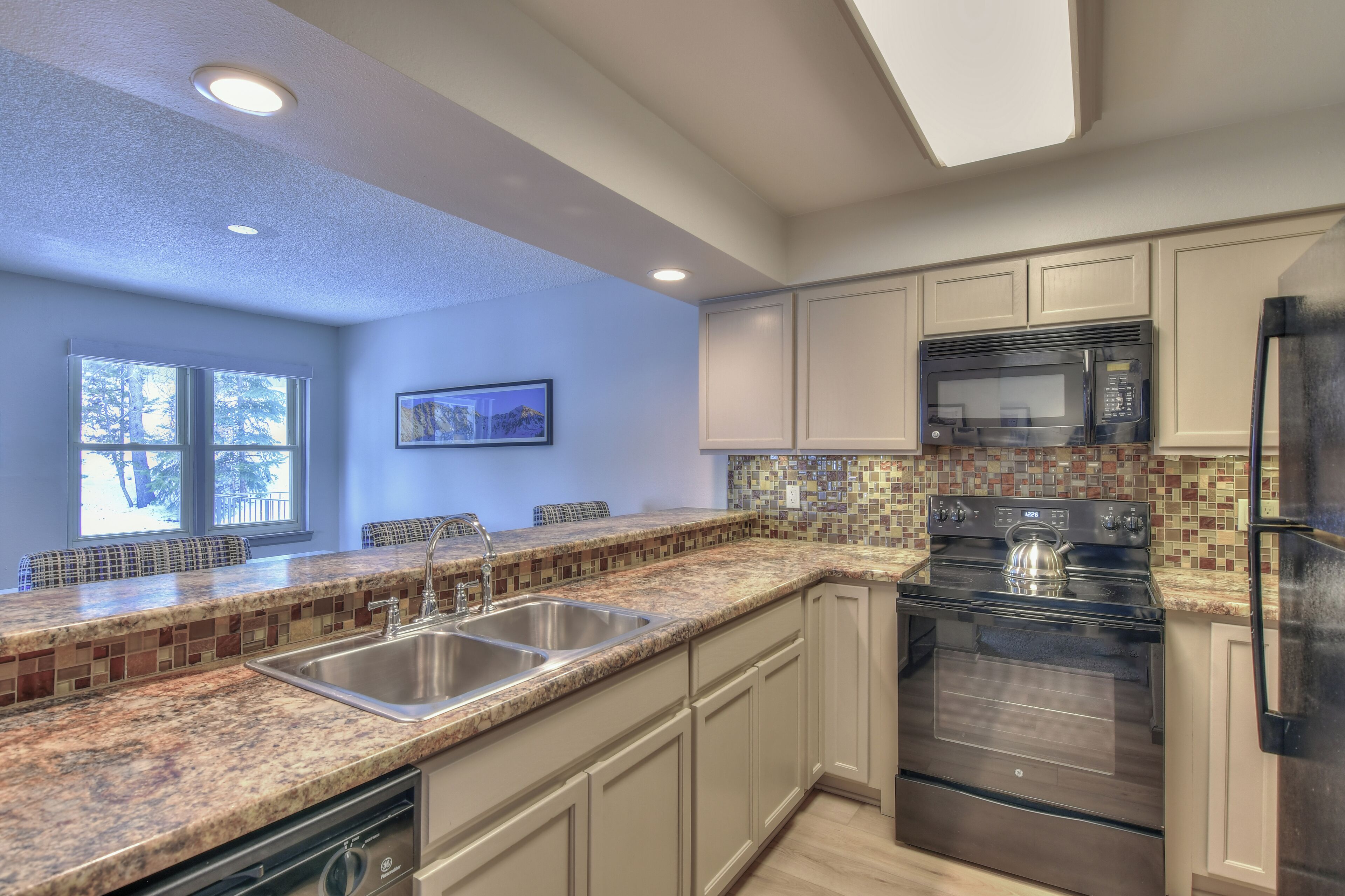 A modern kitchen with granite countertops, stainless steel appliances, and a tiled backsplash.