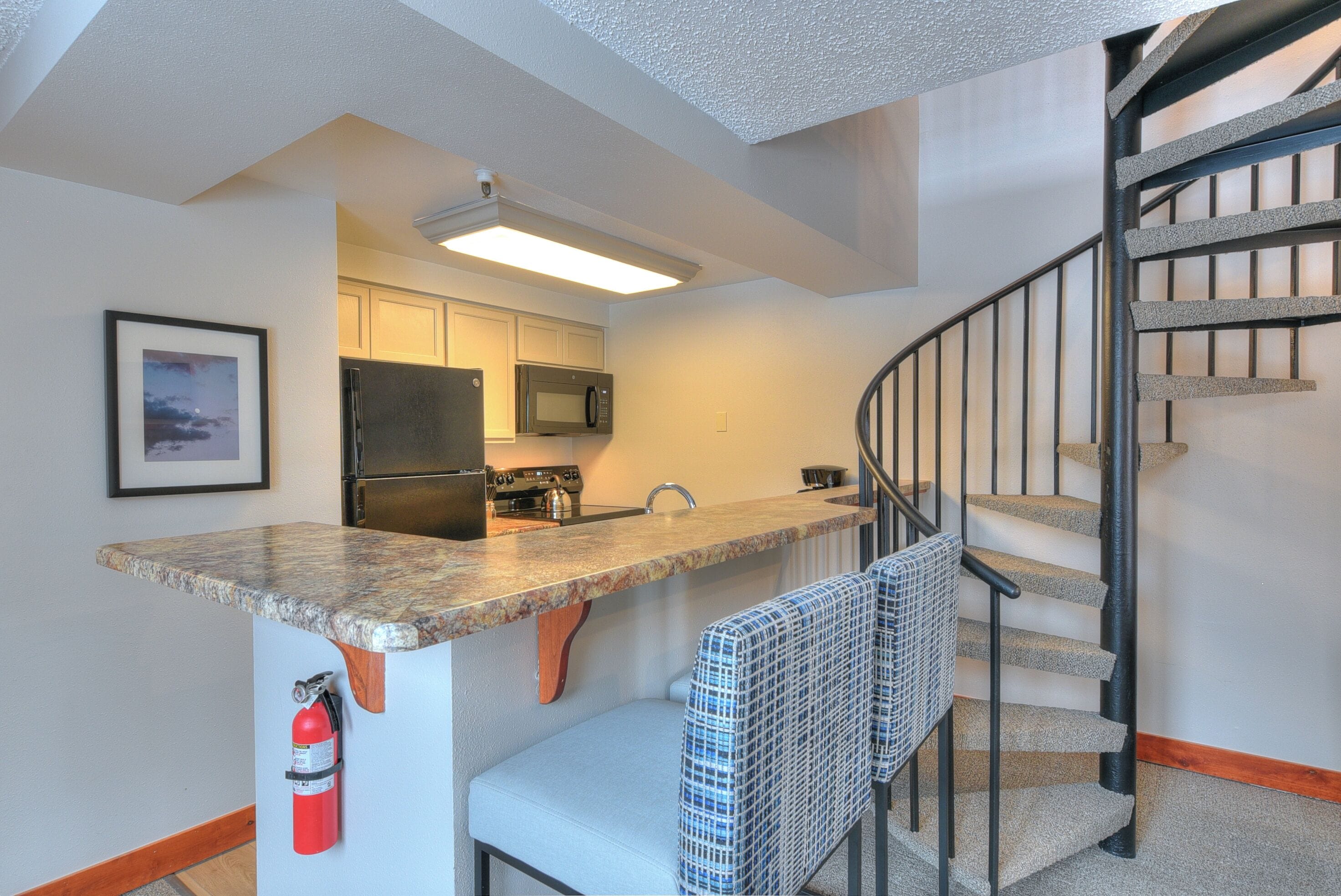 A kitchen with a built-in microwave, a stainless steel refrigerator, and a wooden countertop.