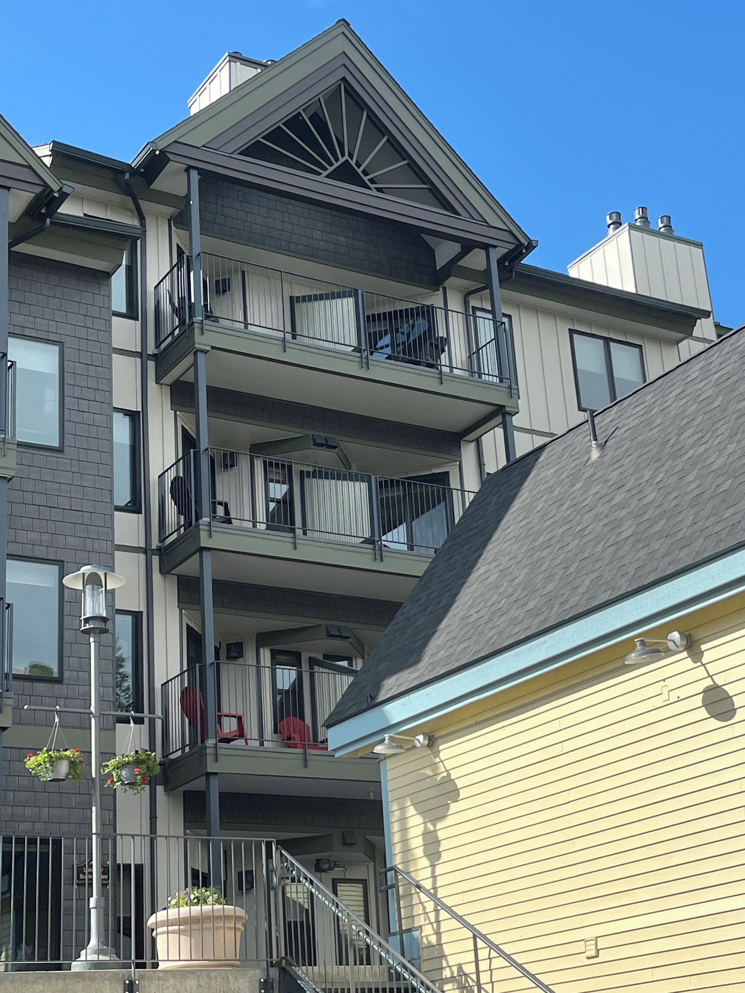 A multi-story residential building with balconies, a visible entrance, and a street lamp.