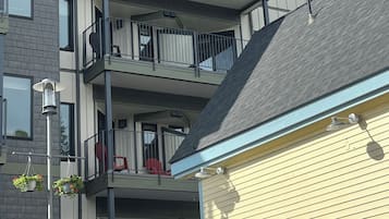 A multi-story residential building with balconies, a visible entrance, and a street lamp.
