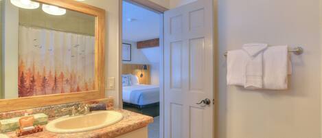 A bathroom with a sink, mirror, and towel rack.