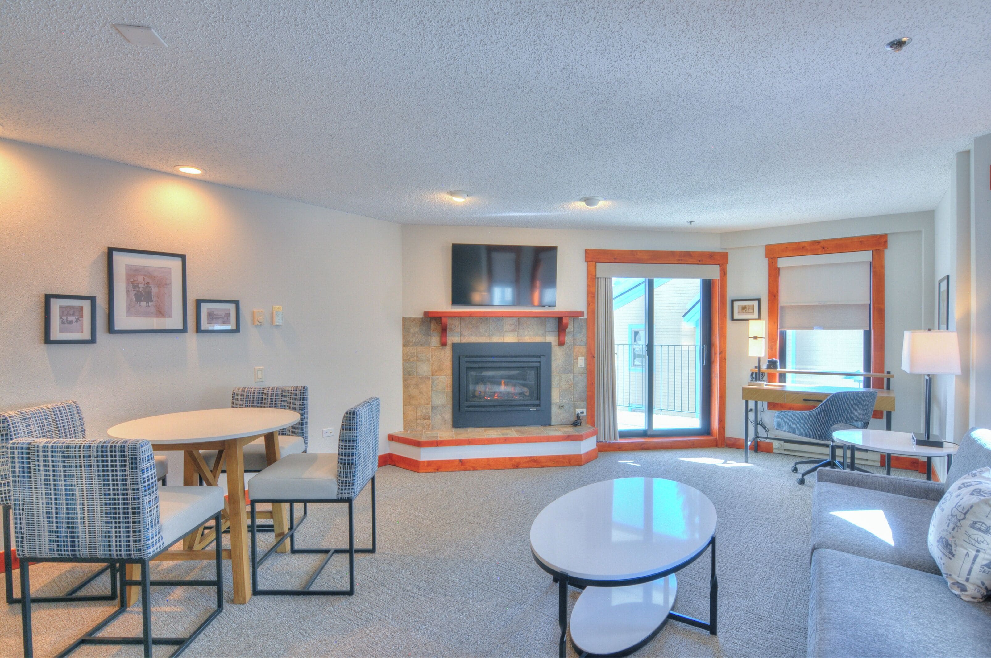 A modern living room with a fireplace, seating area, and a view of the outdoors.