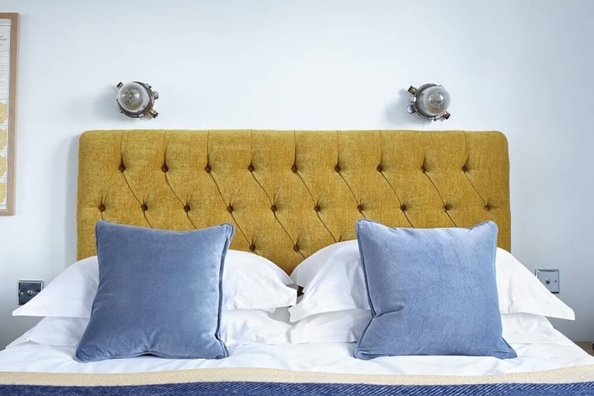 A bed with a tufted headboard, two bedside lamps, and a blue and white bedding set.
