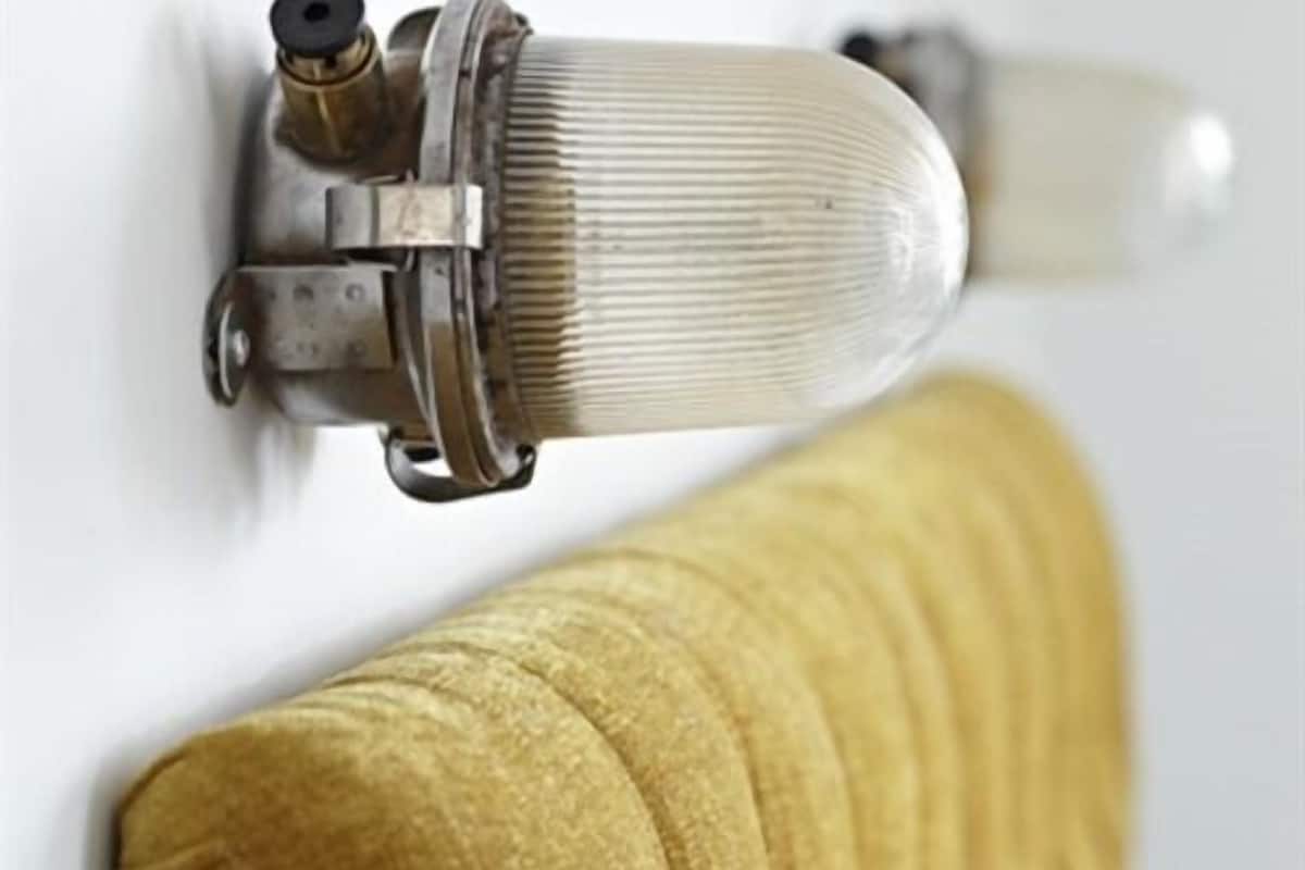 A close-up of a brass valve attached to a white wall, with a yellow textured object partially visible.