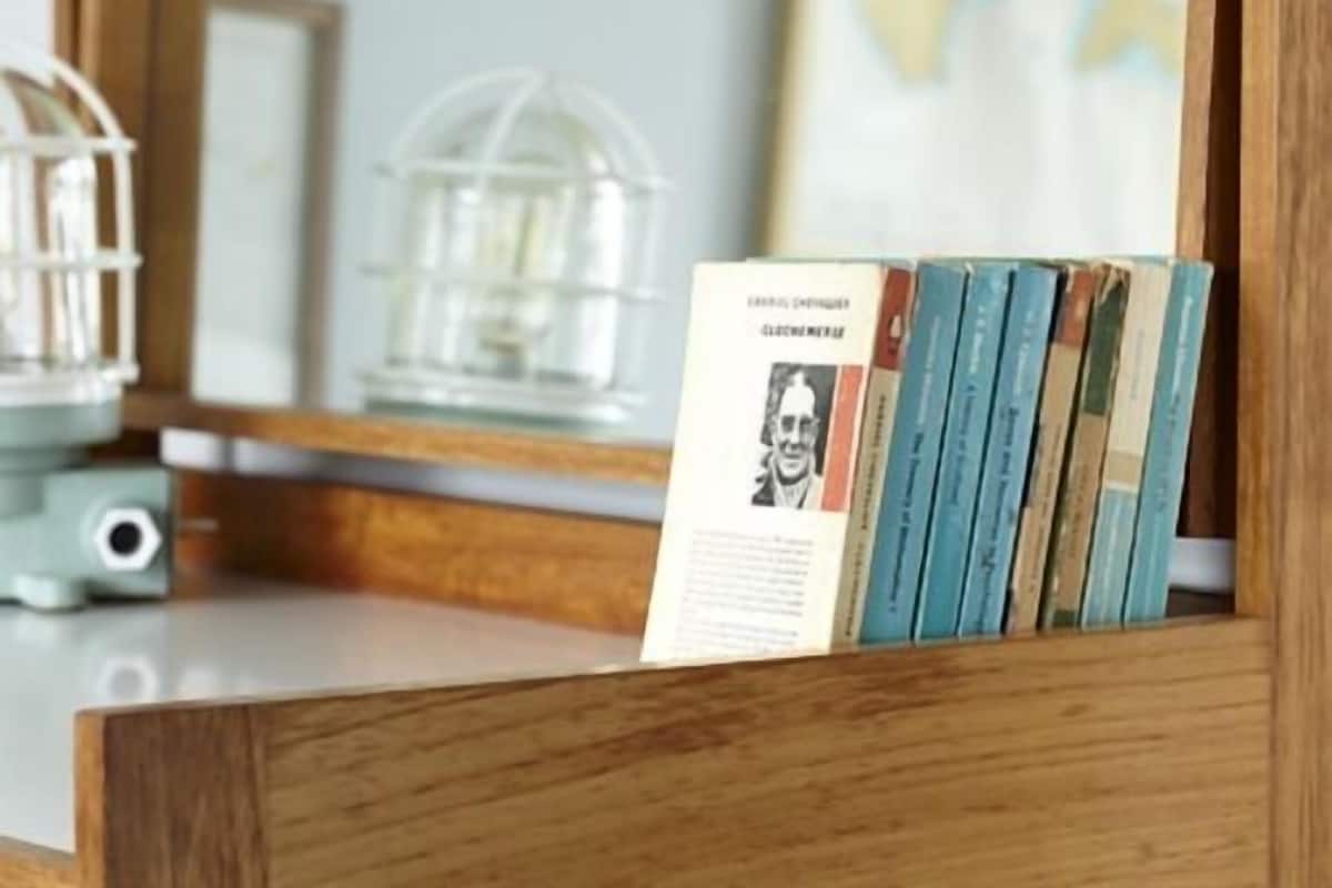 A wooden bookshelf with several books and a framed photograph.