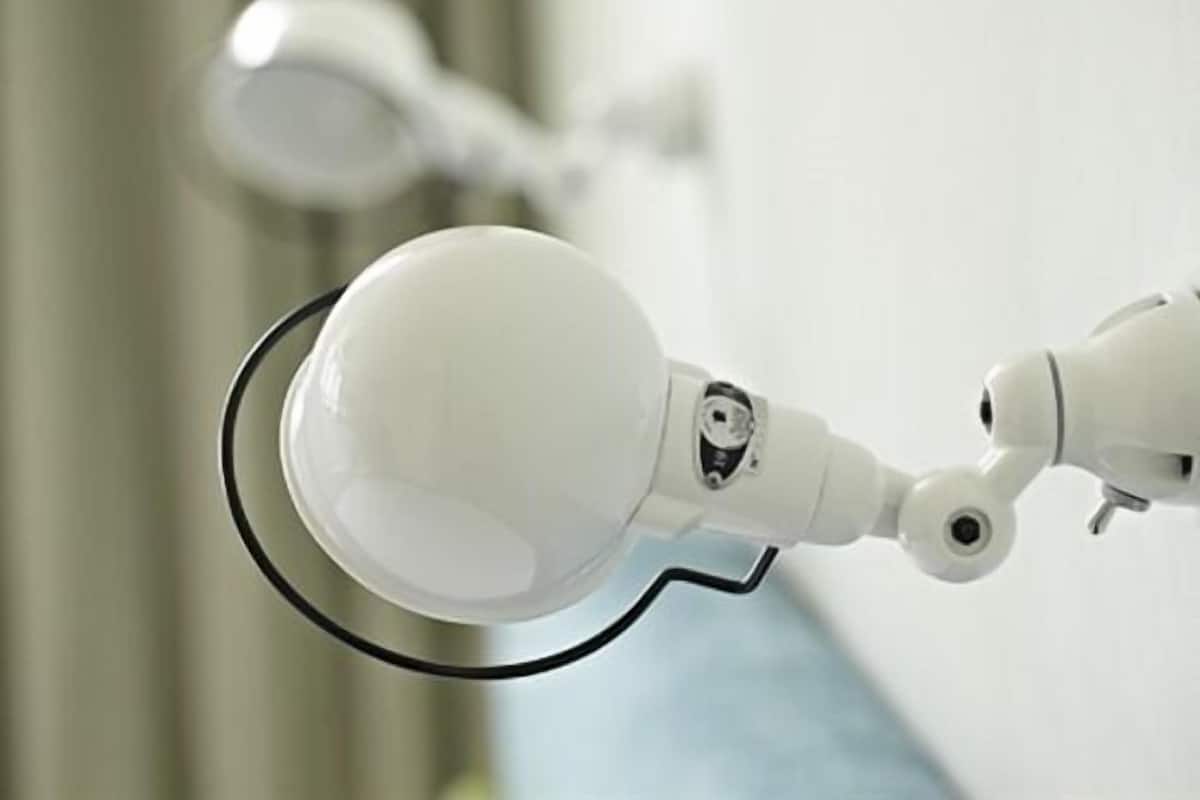 A white, modern, wall-mounted light fixture with a spherical design and a black trim.