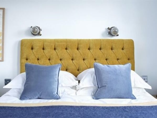 A bed with a tufted headboard, two bedside lamps, and a blue throw blanket. - The Lerryn Hotel (Falmouth)