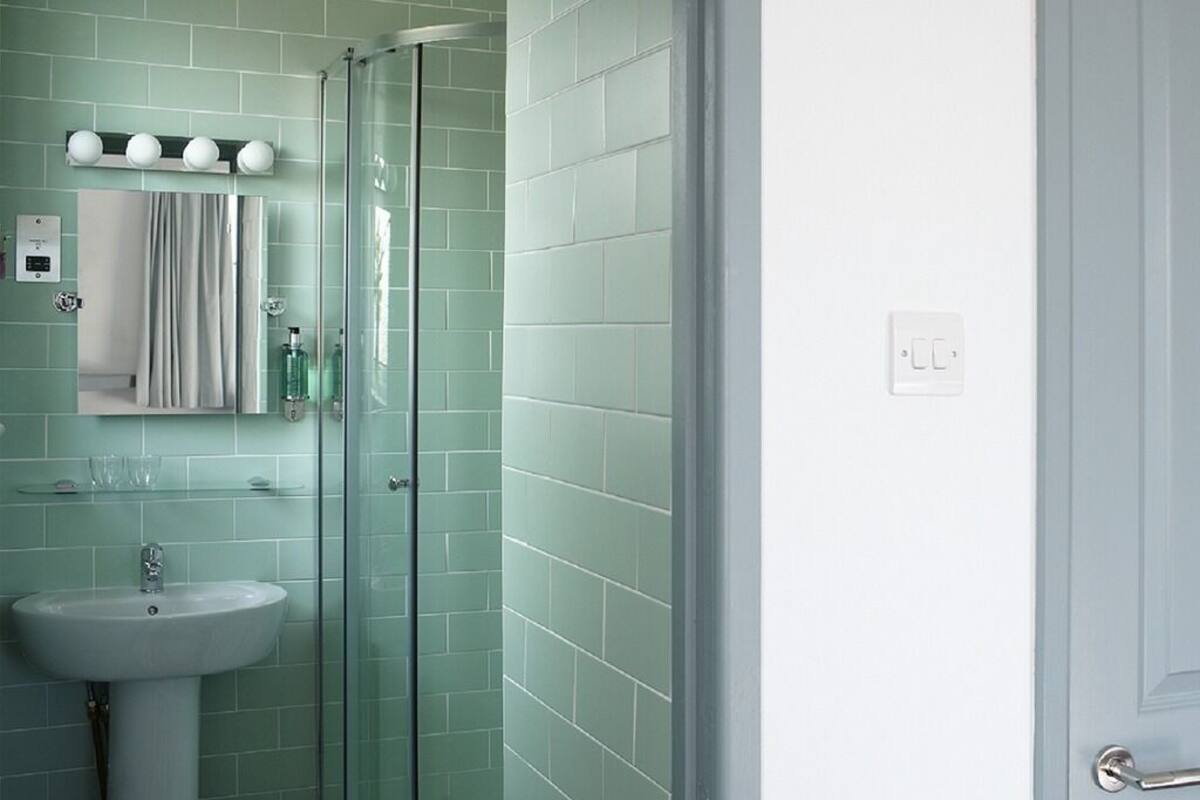 A bathroom with a glass shower enclosure, a sink, and a mirror.