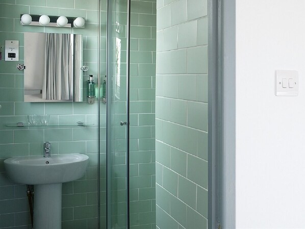 A bathroom with a glass shower enclosure, a sink, and a mirror.