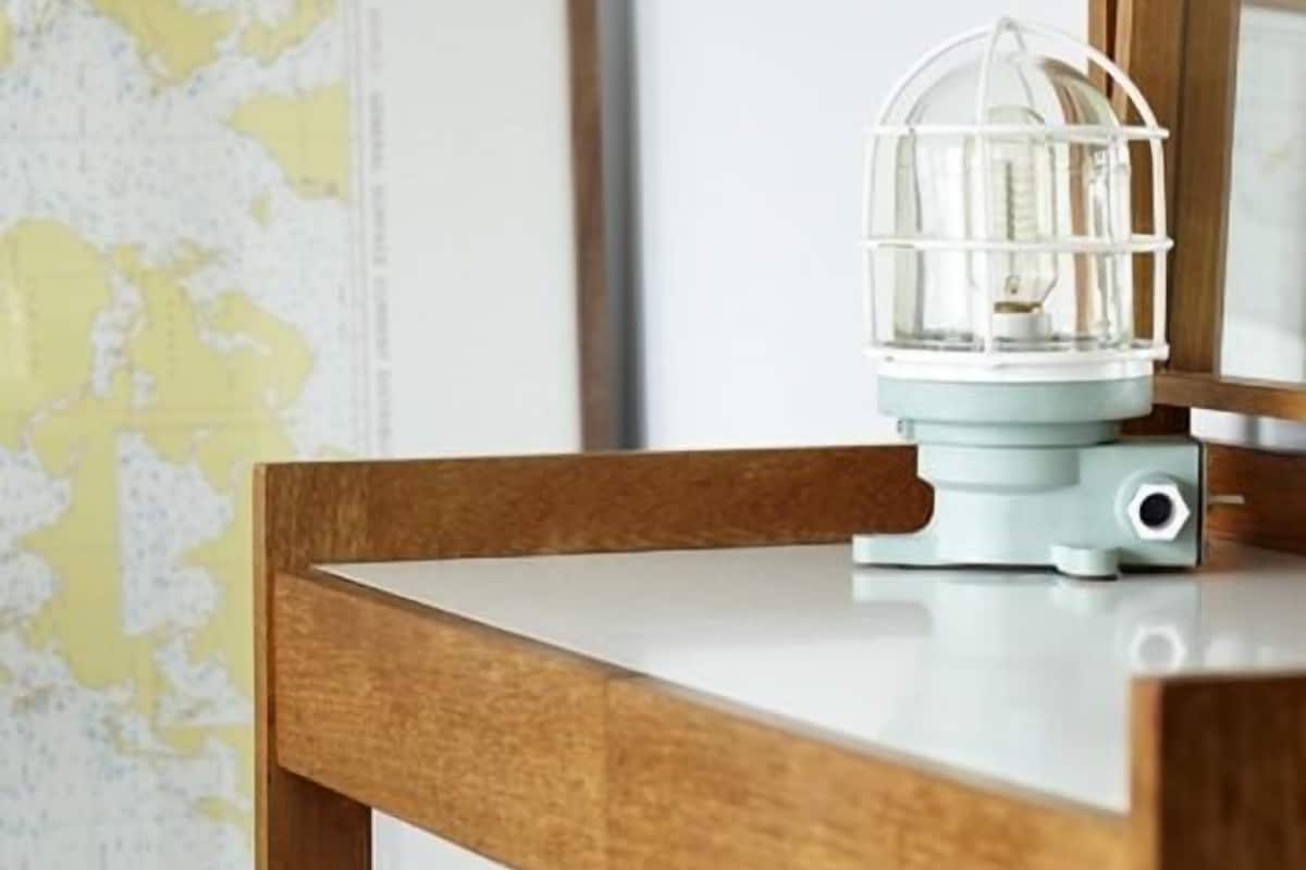 A wooden table with a white lamp on top.