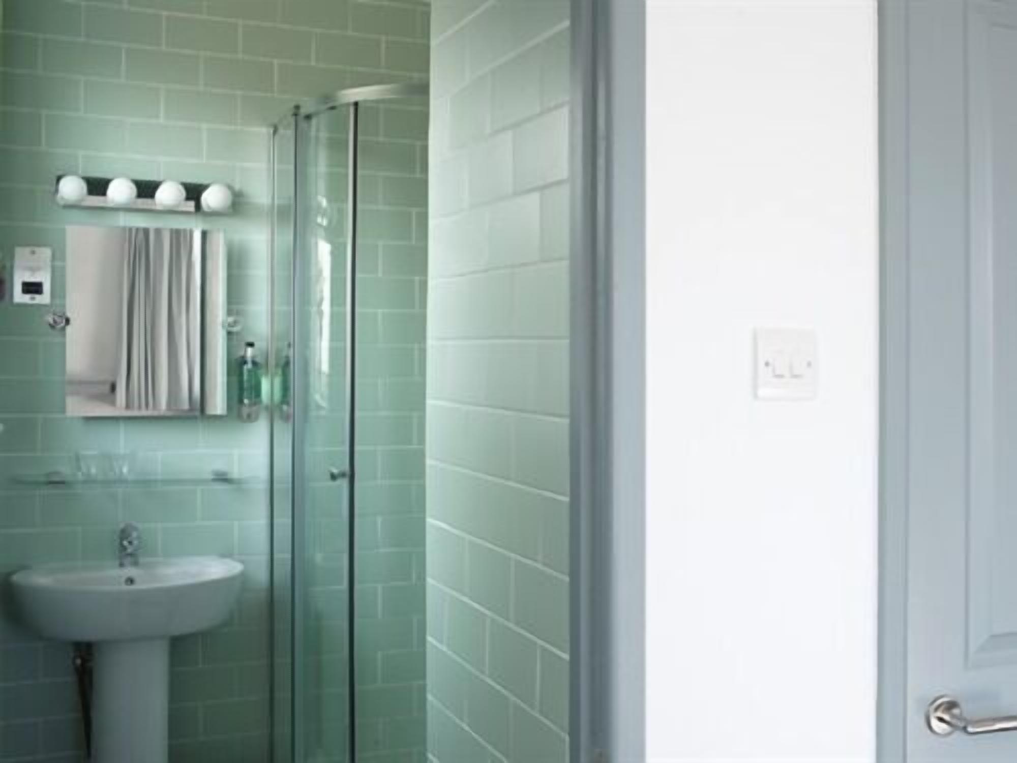 A bathroom with a glass shower enclosure, a sink, and a mirror.