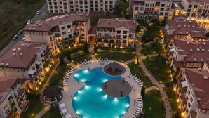 Un hôtel doté d’une piscine centrale, entourée de chaises longues et d’un jardin circulaire.
