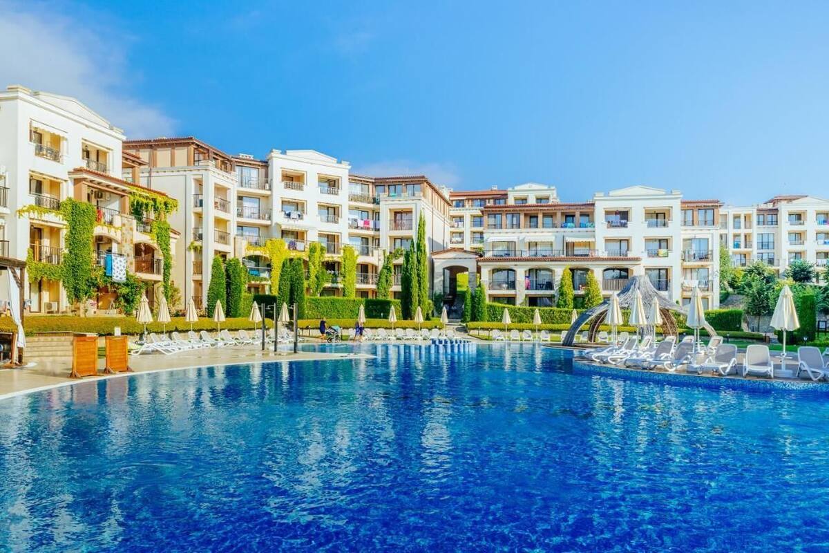 Un hotel con piscina, varios balcones y jardines exuberantes.