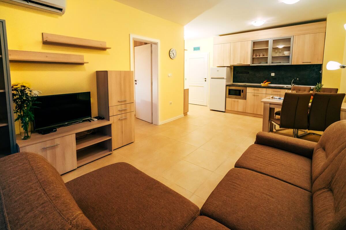 Una sala de estar con televisor de pantalla plana, un sofá y un comedor con mesa y sillas.