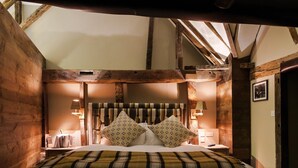 A cozy bedroom with a wooden ceiling, a bed with plaid bedding, and two bedside lamps. - The White Hart, South Harting (Petersfield)