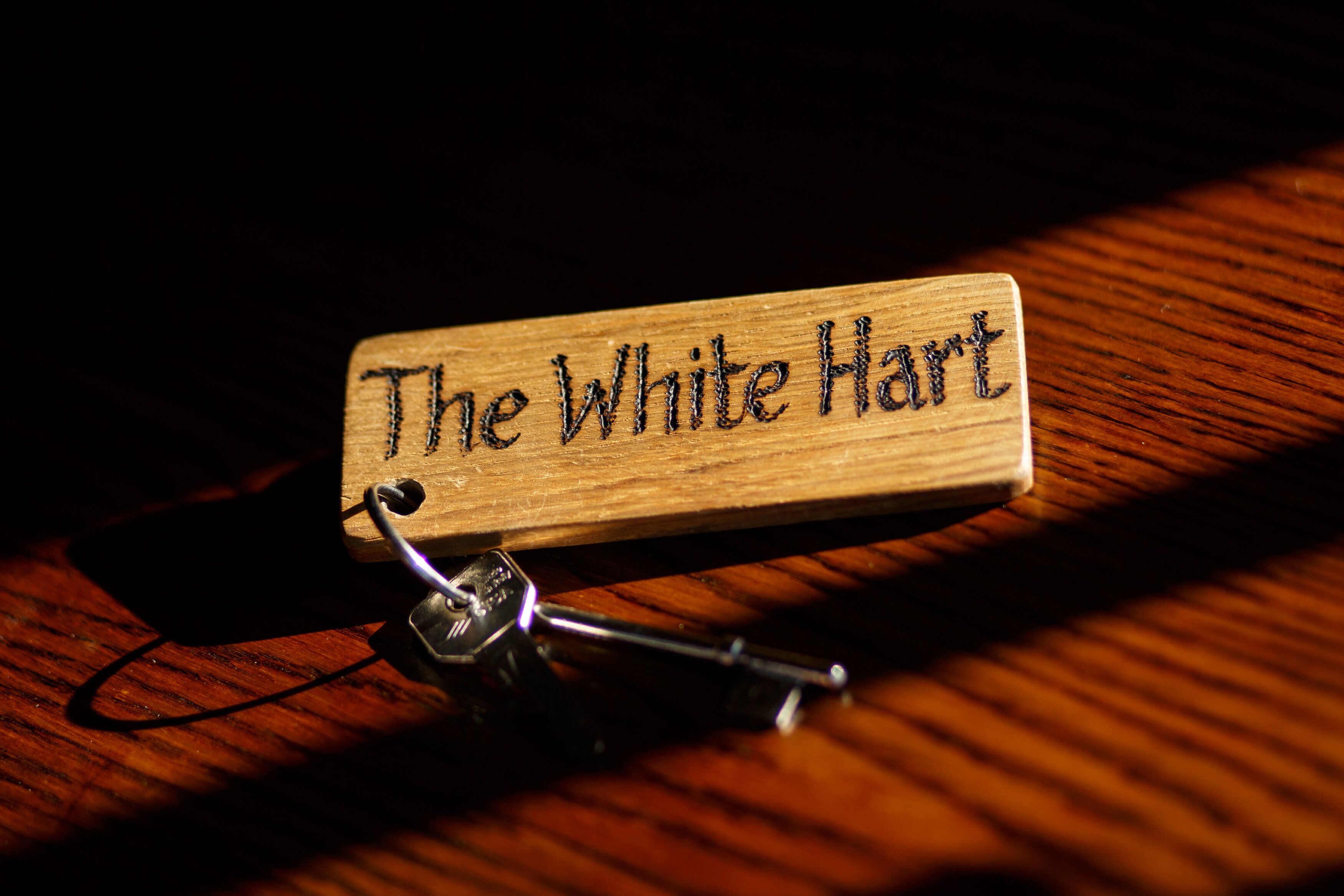 A wooden sign with the text "The White Hart" on a dark background.