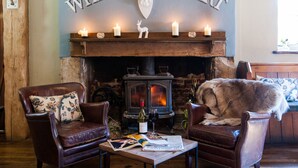 A cozy room with a fireplace, leather chairs, and a dog. - The White Hart, South Harting (Petersfield)